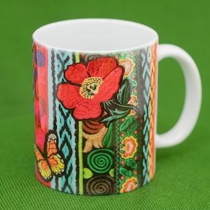 May include: A white ceramic mug with a colorful floral design. The design features a red flower with green leaves, a butterfly, and a variety of colorful stripes and patterns.