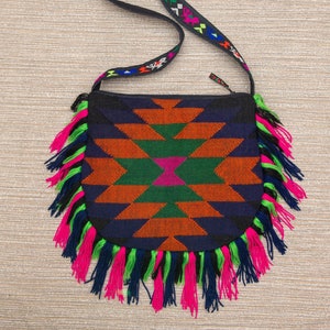 May include: A black and blue crossbody bag with a geometric pattern and fringe trim. The bag has a black strap with colorful embroidery.