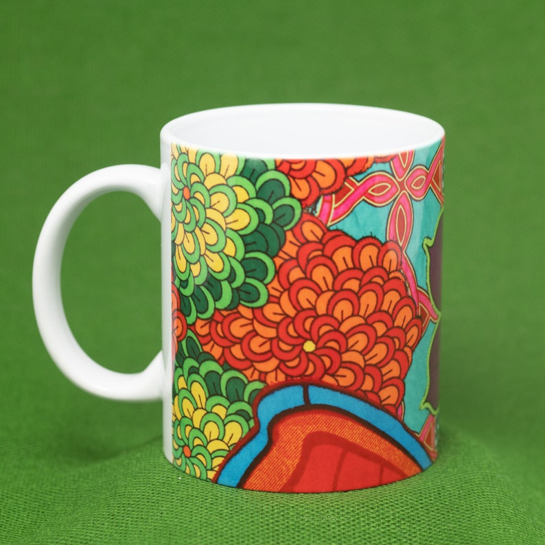 Pode incluir: Uma caneca de cer&acirc;mica branca com um design floral colorido. O design apresenta flores vermelhas, laranja, amarelas, verdes e azuis. A caneca tem uma al&ccedil;a branca.