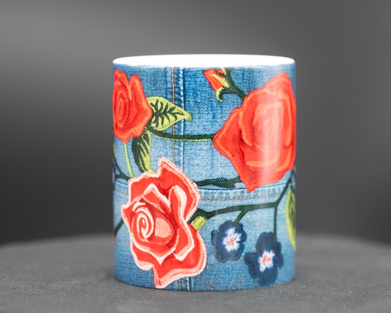 May include: A blue ceramic mug with a denim pattern and red roses embroidered on it.