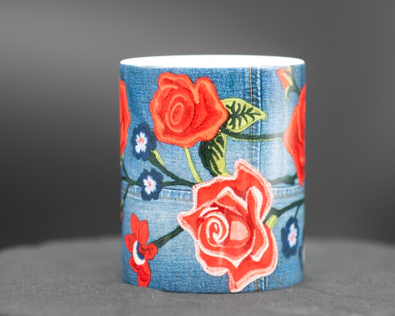 May include: A white ceramic mug with a blue denim pattern and red embroidered roses.