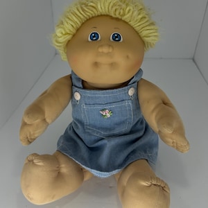 May include: A white ceramic mug with a black handle and the text "But First, Coffee" in a bold, black font. The mug is set against a blurred background, suggesting a cozy setting.