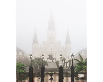 May include: A black wrought iron gate with four lampposts in front of a large white church. The church is obscured by fog.