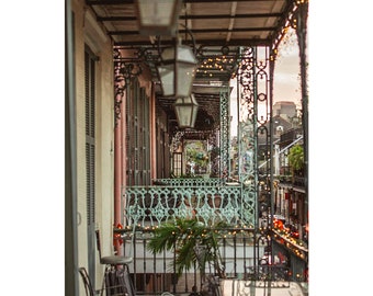 May include: An eye-level shot of a row of balconies with ornate wrought iron railings and decorative lighting. The balconies are painted in shades of pink, green, and beige. A small palm tree sits on one of the balconies.