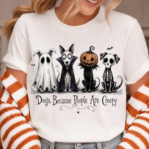 Może przedstawiać: Biały t-shirt z krótkim rękawem z grafiką przedstawiającą cztery psy w kostiumach na Halloween: ducha, wampira, stworzenie z głową dyni oraz szkielet. Poniżej ilustracji znajduje się napis: Dogs, Because People Are Creepy.