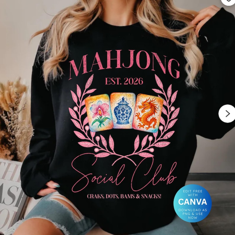 May include: Black sweatshirt with a pink floral design and the words "MAHJONG Social Club" in pink script. The design includes three illustrated Mahjong tiles and the text "EST. 2026". The bottom of the design reads "CRAKS, DOTS, BAMS & SNACKS!"