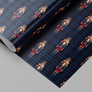 May include: A roll of wrapping paper with a repeating pattern of toy nutcrackers on a navy blue plaid background. The nutcrackers are in red, blue, and gold. The paper is partially rolled.