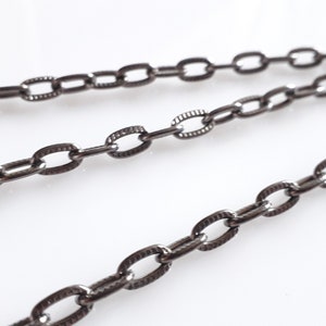 May include: A close-up of a black chain with oval links. The chain is made of metal and has a matte finish.
