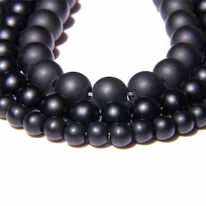 Peut inclure: Un brin de perles rondes noires mates. Les perles sont de différentes tailles et sont enfilées sur un fil transparent.