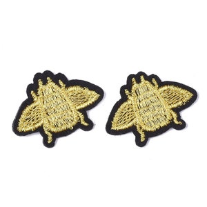 Peut inclure: Deux patchs brodés d'abeilles dorées sur fond noir. Les abeilles sont face à face.