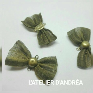 Puede incluir: Tres lazos de tela verde con detalles dorados. Los lazos tienen un bucle en la parte posterior para sujetarlos a una prenda.