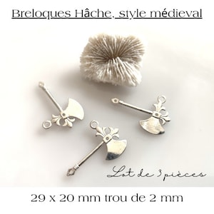 Puede incluir: Tres colgantes de hacha plateados, de estilo medieval. Los colgantes miden aproximadamente 2,9 cm x 2 cm. El texto de la imagen dice "Breloques Hâche, style médiéval", "Lot de 3 pièces" y "29 x 20 mm trou de 2 mm".