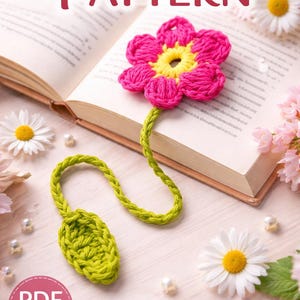 Puede incluir: Un marcapáginas de ganchillo con forma de flor rosa y centro amarillo, unido a un tallo verde. El marcapáginas está colocado en un libro abierto. Se ven las palabras "CROCHET PATTERN" y "Flower Bookmark".