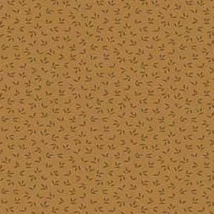 May include: A close-up of a fabric featuring a repeating pattern of small, dark green leaf shapes on a tan background. The leaves are evenly spaced, creating a textured appearance. The fabric has a warm, earthy tone.