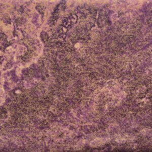 Puede incluir: Tela morada con un patrón de mármol dorado. La tela tiene una superficie texturizada.