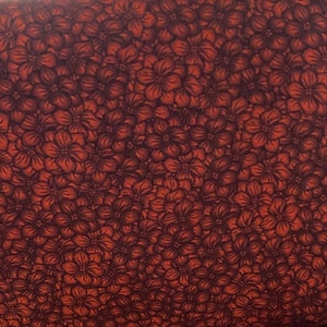 Könnte beinhalten: Ein roter Stoff mit einem dunkelbraunen Blumenmuster. Die Blumen sind klein und dicht gepackt, was ein geschäftiges und kompliziertes Design ergibt.