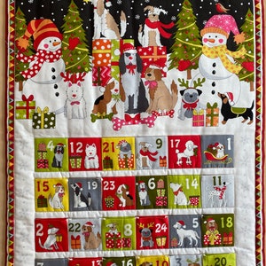 Peut inclure: Un calendrier de l'avent de Noël avec une scène d'hiver représentant des bonhommes de neige, des chiens et des cadeaux. Chaque jour a une poche numérotée avec une illustration de chien différente. Les numéros 1 à 24 sont visibles sur les poches.