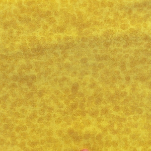 Op de afbeelding: Close-up van een gele stof met een gevlekt patroon. De stof heeft een getextureerd uiterlijk, met kleine, onregelmatige vormen in een iets donkerdere tint geel verspreid over het oppervlak. Het algehele effect is een warme, gouden tint.