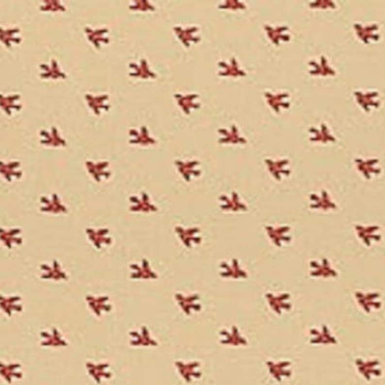 May include: Cream-coloured fabric featuring a repeating pattern of small, red bow tie shapes. The bow ties are evenly spaced, creating a consistent design. The fabric appears to be of a light to medium weight, suitable for various applications.