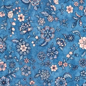 Può includere: Un tessuto blu con un motivo floreale in tonalità di rosa, bianco e blu. I fiori sono piccoli e delicati, e il motivo si ripete su tutto il tessuto.