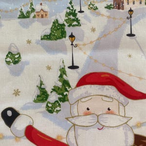 May include: A festive fabric featuring a winter scene with Santa Claus. The design includes snow-covered hills, evergreen trees, houses, and street lamps. Santa is wearing a red suit and hat, with a white beard and a friendly expression.