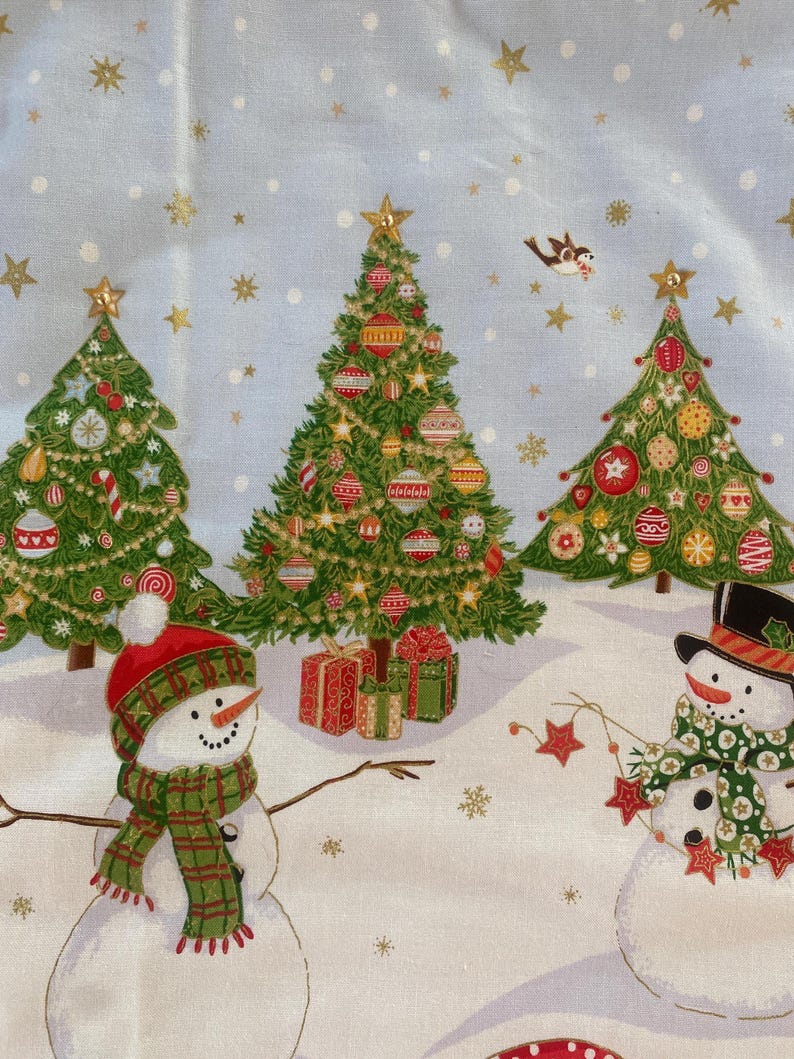 May include: A light blue Christmas-themed fabric featuring decorated green Christmas trees, snowmen, and gift boxes. The trees are adorned with ornaments and topped with gold stars. Snowmen wear hats and scarves. Gold stars and snowflakes are scattered across the background.