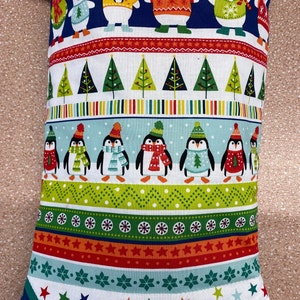 May include: A blue and white Christmas stocking with a red cuff. The stocking features a pattern of penguins, polar bears, and Christmas trees. The stocking is decorated with stars, snowflakes, and stripes.