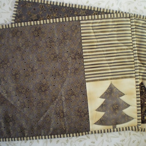 Peut inclure: Trois sets de table en tissu brun et crème avec un motif répétitif de cœurs, de rayures et un motif d'arbre stylisé.