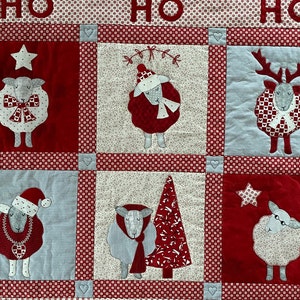 以下が含まれることがあります： 赤、白、青のパッチワークキルトで、クリスマスのテーマです。キルトには、さまざまな羊とトナカイのデザイン、クリスマスツリーと星が描かれています。キルトはさまざまな生地とテクスチャで作られており、どんな家にもお祝いの雰囲気を加えるのに最適です。