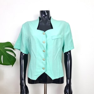 May include: A light blue short-sleeved blouse with a button-up front and a pointed collar.