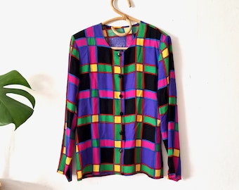 Può includere: Una camicia a maniche lunghe con bottoni e un motivo geometrico colorato in tonalità di viola, rosa, verde, giallo, nero e rosso.