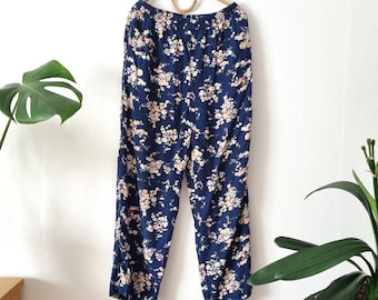Puede incluir: Pantalón azul marino con estampado floral. El pantalón tiene pierna ancha y cintura elástica.
