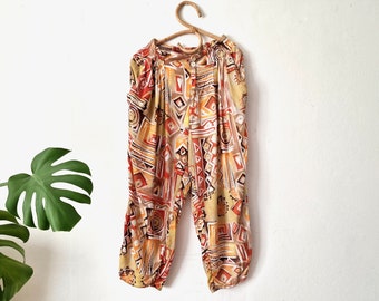 Könnte beinhalten: Eine Hose mit weitem Bein und lockerer Passform in braunen, orangen und gelben Mustern mit geometrischem Design.