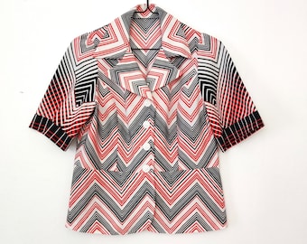 May include: A white, red, and black short-sleeved button-up shirt with a geometric chevron pattern.