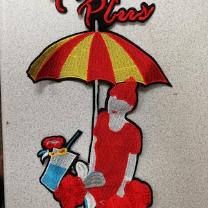 May include: Embroidered patch with a woman under a red and yellow umbrella. The woman wears a red dress and hat. A drink and flowers are also included in the design. The text "Five Plus" is at the top of the patch.