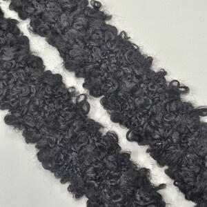 May include: Two strips of black curly faux fur fabric.