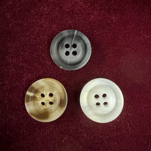 May include: Three buttons, one black, one white, and one brown, each with four holes.