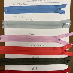 May include: A sample card showing different colors of zipper tape. The colors are sky blue, light blue, pink, burnt orange, olive, and red. The card also includes the text "6" Sky Blue", "8" Zips LT Blue", "PINK", "BURNT ORANGE", "OLIVE", and "Red".