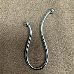 May include: A silver metal shower curtain hook with rounded ends.