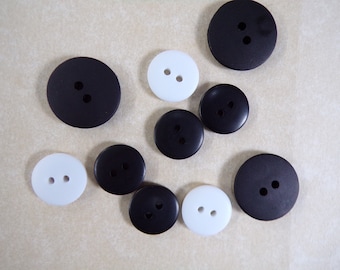 May include: Assortment of black and white buttons with two holes each. The buttons are round and have a smooth surface.