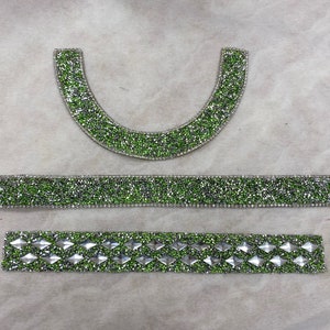 May include: Three pieces of green and silver rhinestone trim. The trim is made of small, round rhinestones that are sewn together in a pattern. The trim is perfect for adding a touch of sparkle to any project.