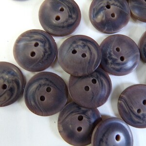 Könnte beinhalten: Eine Sammlung brauner Wirbelknöpfe mit jeweils zwei Löchern. Die Knöpfe sind aus Kunststoff und haben eine marmorierte Optik.