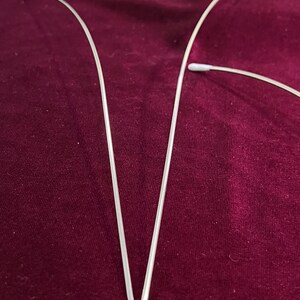 May include: Two silver wire hangers with white plastic tips. The hangers are bent into a V-shape.