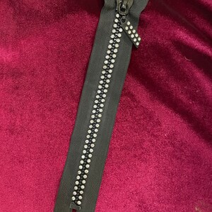 May include: A black zipper with a silver pull and clear rhinestone embellishments.