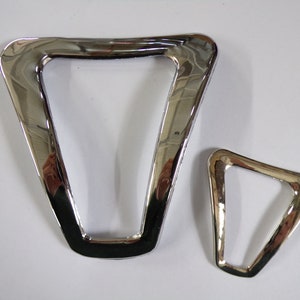 May include: Two shiny, chrome-finished, triangular metal objects. One is significantly larger than the other. The objects have a smooth, reflective surface, and are set against a plain white background. The larger triangle is approximately 5 inches wide.