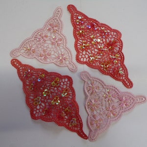 May include: Four triangle-shaped lace appliques with sequins. Two are pink and two are red.