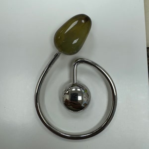 Könnte beinhalten: Ein silberner Ring mit einem grünen Stein daran. Der Ring ist kreisförmig mit einer kleinen Kugel in der Mitte.