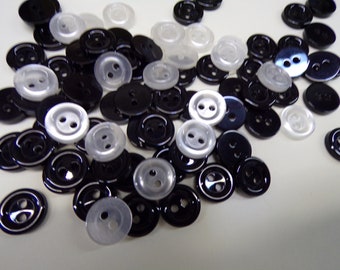 May include: A pile of black and white plastic buttons. The buttons are round and have two holes.