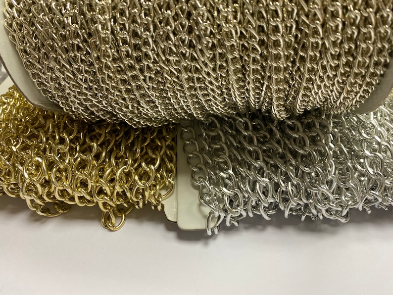 May include: Two spools of chain, one gold and one silver. The chains are both the same style, with a linked pattern.