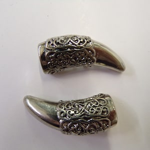 Puede incluir: Dos piezas decorativas de plata en forma de garra con intrincados diseños de filigrana.